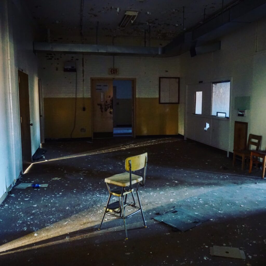Abandoned room with peeling paint and chair.